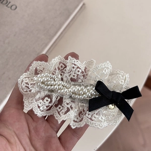 Detailed shot of white lace hair clip with pearls and a small black bow accent