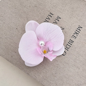 Detail of elegant orchid hair clip with realistic fabric petals and pearl center