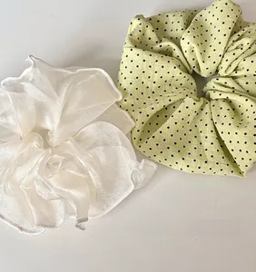 Détail de deux chouchous de style français en satin blanc et à pois verts élégants