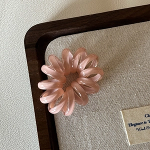 Nahaufnahme eines rosa Spirallinien-Haargummis auf einem rustikalen Holztablett Deko