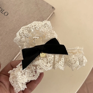 Close-up of white lace hair claw clip with black satin bow and golden LUNA pendant