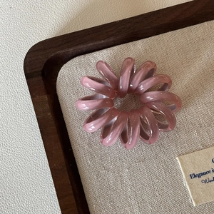 Nahaufnahme eines rosa Spirale-Telefonkabel-Haargummis auf einem Holztablett ohne Abdrücke