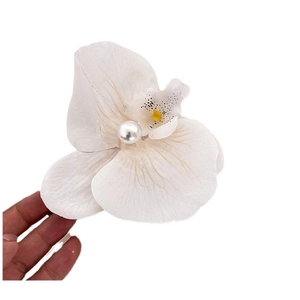 Elegant white orchid flower hair clip featuring a large faux pearl center held in hand