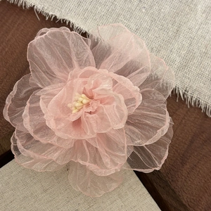 Exquisite pink tulle peony hair clip with lifelike yellow stamens on rustic background