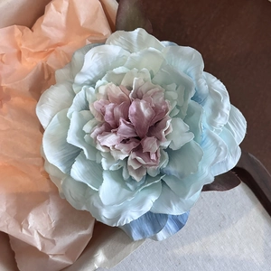 Close-up of layered blue and pink fabric peony hair clip with realistic petal texture