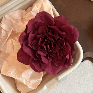Macro detail of dark red artificial peony flower clip with realistic silk fabric petals