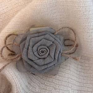 Handmade gray fabric rose hair claw clip with vintage linen bow on white knit background