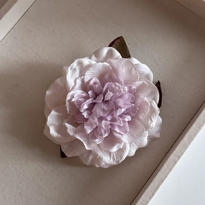 Close-up of layers of handmade pink and purple silk peony flower petals hair clip