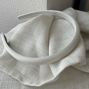 Close-up of cream textured satin headband with delicate fabric detail and black lining
