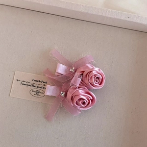 Detalle de horquillas de rosas de satén rosa hechas a mano con cristal central y cintas