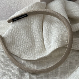Elegant beige satin headband with handmade label on cream linen background