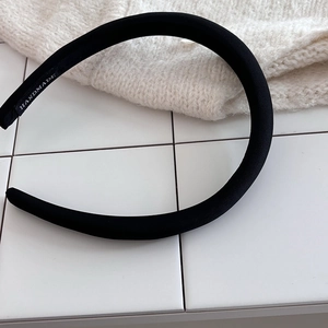 Detail of a handmade black satin headband featuring a premium quality fabric interior label
