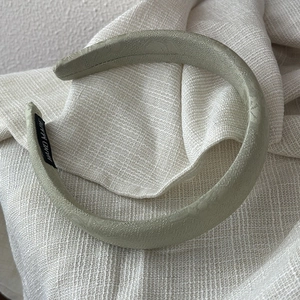 Detail of light green satin headband showing textured fabric and handmade label