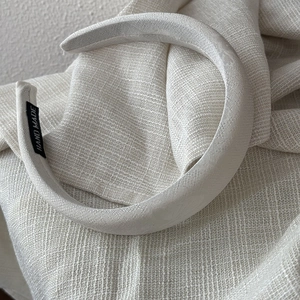 Detail of satin headband with woven texture and handmade tag on neutral fabric