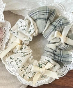 Détail d'un chouchou à fleurs et carreaux avec dentelle et petits nœuds crème