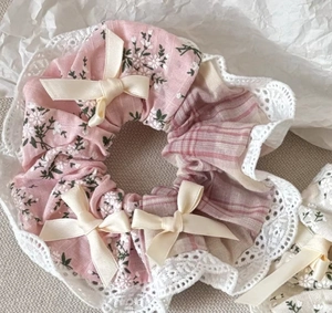 Détail d'un chouchou rose à fleurs avec dentelle et petits nœuds en ruban beige