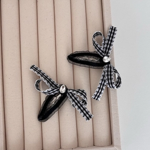 Detail of checkered bow hair clips with rhinestone accents and black tulle on beige velvet