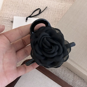 Detailansicht der geschichteten schwarzen Stoff-Kamelienblüte auf einer Haarspange