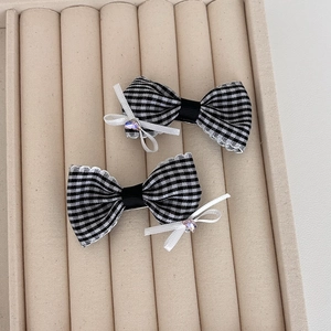Close-up of black and white checkered bow hair clips with rhinestones in a velvet box
