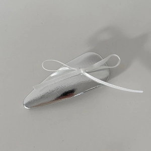 Détail d'une barrette à paillettes argentées ornée d'un nœud en satin blanc élégant