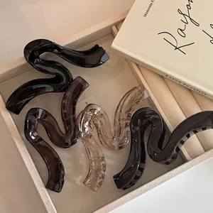 S-shaped geometric wave hair claws in black and amber colors on a display tray