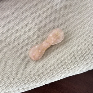 Pink marble acetate bow hair clip with France Handmade logo on beige textured fabric