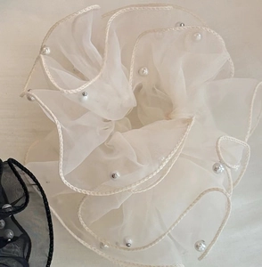 Détail d'un chouchou en organza avec perles synthétiques en crème et noir élégant