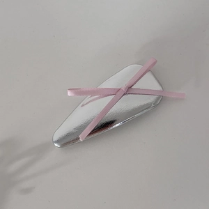 Gros plan sur une barrette triangulaire en métal argenté avec un nœud en ruban rose