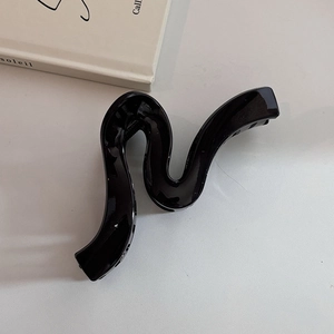 Minimalist black wave geometric hair claw clip with glossy finish on a white surface