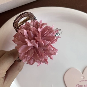 Detail einer Haarspange mit rosa Stoffblume, mehrschichtigen Blüten und Goldfeder