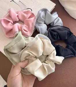 Close-up of five colorful satin scrunchies with wavy edges on a book background
