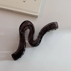 Detail shot of a dark brown wavy claw clip with a sleek resin finish on a white background