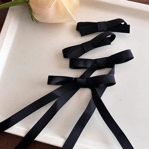 Détail de pinces à nœud en ruban gros-grain noir avec texture côtelée et longs rubans