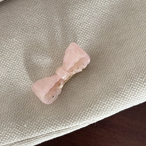 Detailed macro view of a pink acetate bow hair clip with marble texture on beige fabric