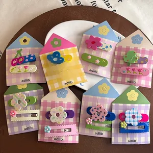 Vue à plat de barrettes en résine colorées avec motifs cerises et fleurs sur supports