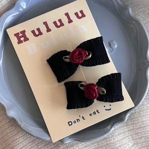 Paire de barrettes à nœuds plissés noirs avec roses en tissu rouge et feuilles sur carte