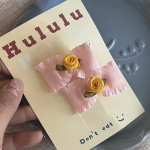 Détail de barrettes à nœuds roses avec roses jaunes sur carte pour enfants