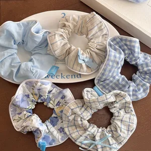Dettaglio di elastici scrunchie blu stile balletto con fiocchi e motivi a quadri