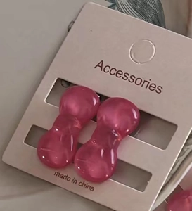 Macro shot of cute mini translucent pink resin bow earrings on a beige display card