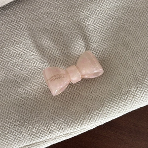 Macro detail of a pink acetate bow hair clip with gold France Handmade lettering