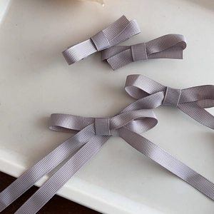 Détail de barrettes à nœuds en ruban gros-grain violet avec de longs rubans sur un plateau