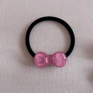 Close-up of a pink translucent resin bow hair tie with a black elastic rubber band
