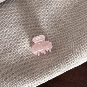 Close-up of small pink acetate hair claw clip with marble texture on linen fabric