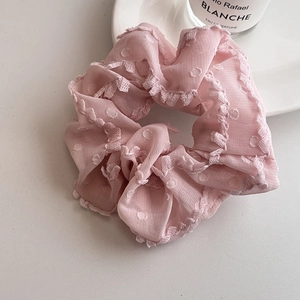 Détail du chouchou en dentelle rose avec motifs à pois et tissu en mousseline plissé
