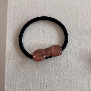 Detail of high elastic black hair tie featuring a brown translucent resin bow decoration