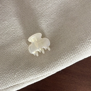 Detailed view of a mini cream-white acetate hair clip with a smooth pearlescent finish
