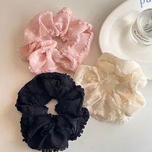 Lot de trois chouchous en dentelle rose, beige et noir avec motifs à carreaux crème
