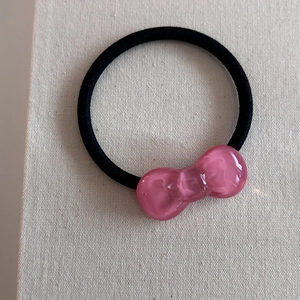 Close-up of pink ribbon hair tie with a shiny jelly-like texture and black elastic band
