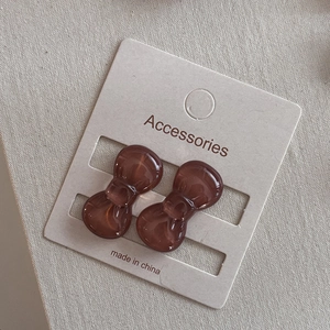 Close-up of mini brown resin bow hair clips on premium textured display card