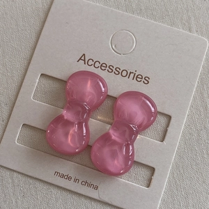 Close-up of pink resin bow hair clips on card with soft fabric background texture